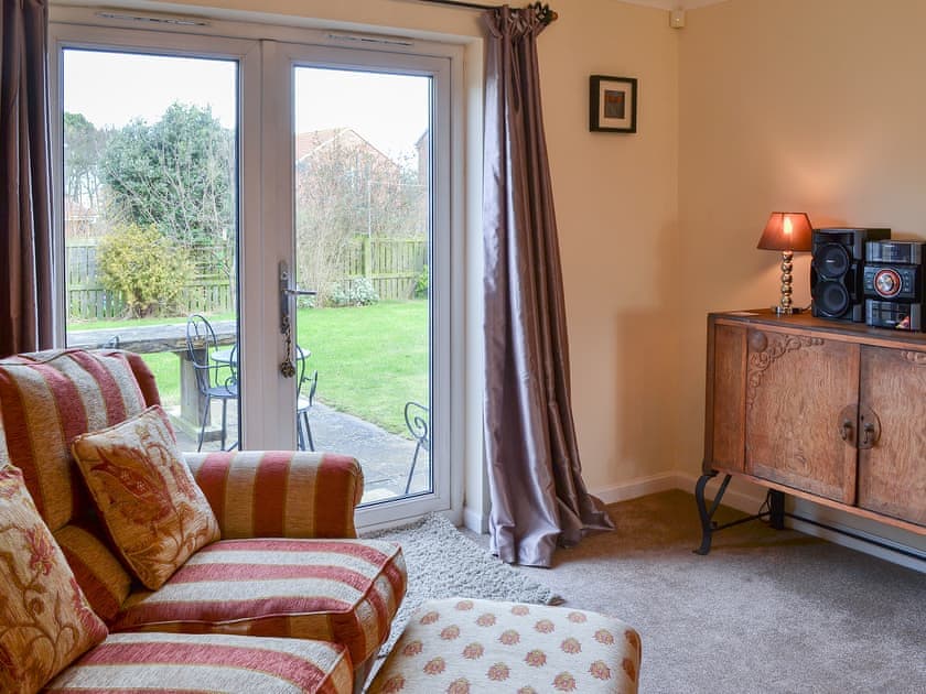 Living room with patio doors leading to the garden | Sand Castles, Seahouses