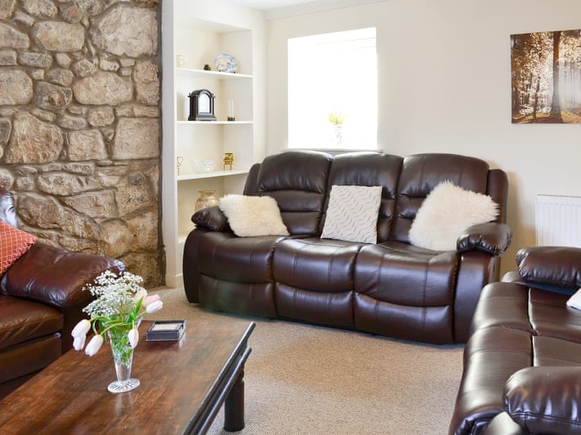 Comfy seating and an exposed stone feature wall in living room | The Granary - Rousland Cottages, Linlithgow