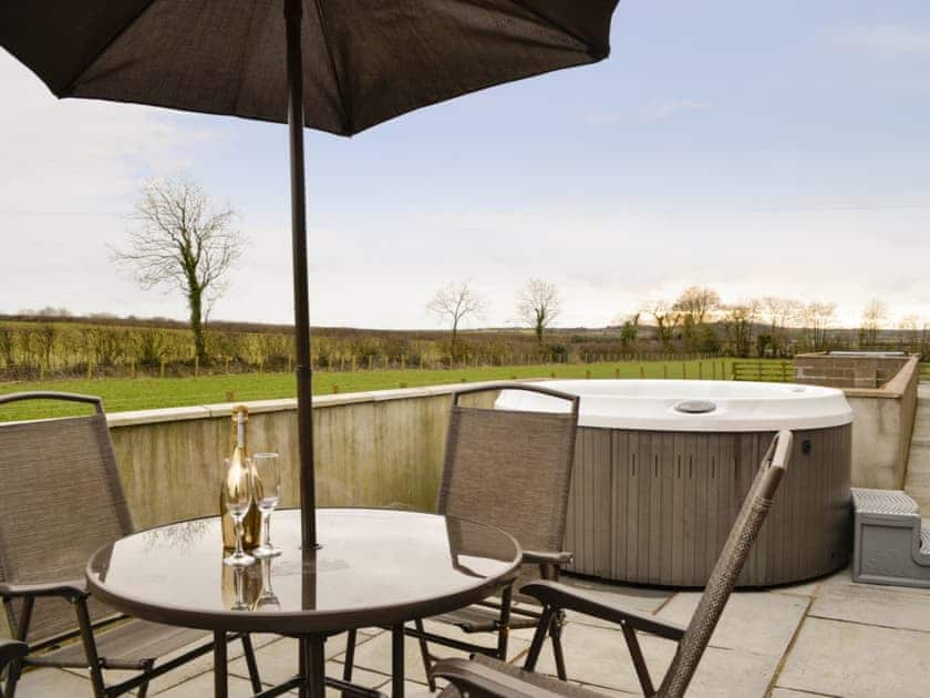 Paved patio area with hot-tub and outdoor furniture | The Old Byre - West House Farm, Dearham, near Maryport