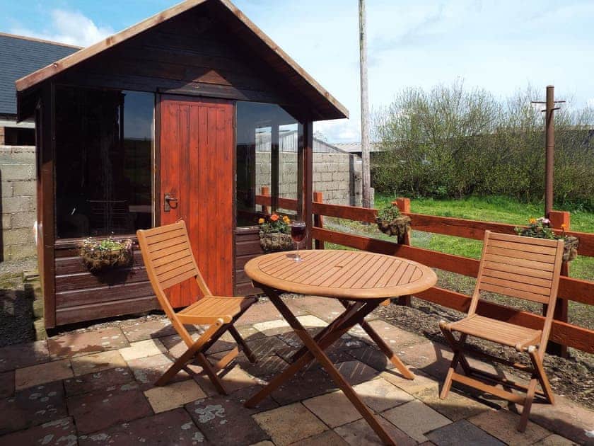 Paved patio with furniture and summerhouse | The Bothy - Clauchan Farm, near Gatehouse of Fleet