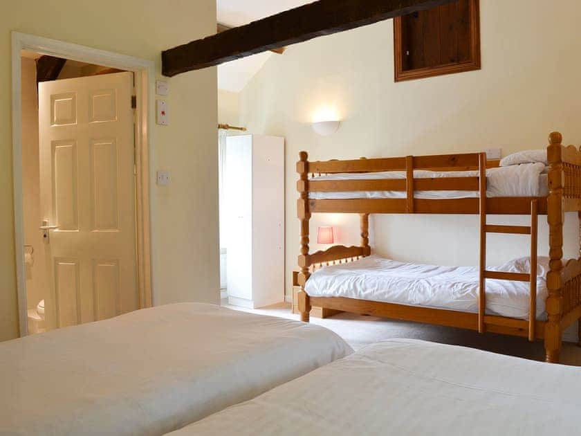 Bedroom with twin beds and children’s bunk beds | Granary - Trimstone Manor Cottages, Trimstone, near Woolacombe
