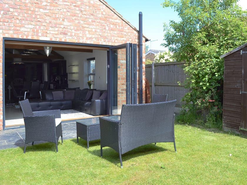 Bi-fold doors opening onto a flagged patio with seating area | The Old Stables, South Cave, near Beverley