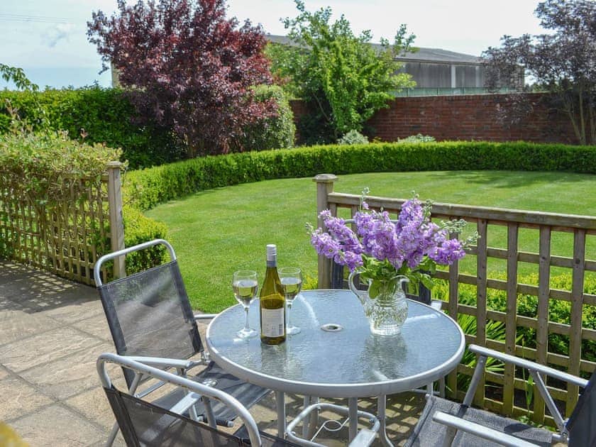 Patio with seating area overlooking the lawn | Stables Cottage - Mackinder Farms, Brayton, Selby