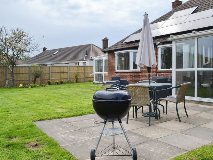 Lawned garden with patio and barbecue | Sea La Vie, Mundesley, near North Walsham