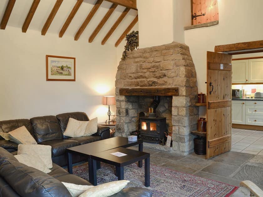 Characterful living room with Peak Stone fireplace with black cast iron stove | Spring Cottage, Hollinsclough, near Buxton