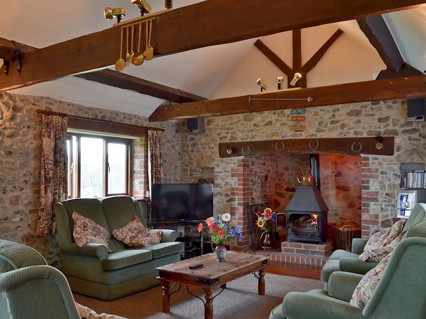 Exposed stonework, wooden beams and an inglenook fireplace with wood burner complete the charming living area of this traditional cottage | Stable Cottage, Colyford, near Seaton