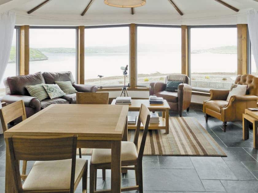 Living/dining room with 180-degree bay window looking directly onto beach | Beach Bay Cottage, Carnish, Uig, Isle of Lewis