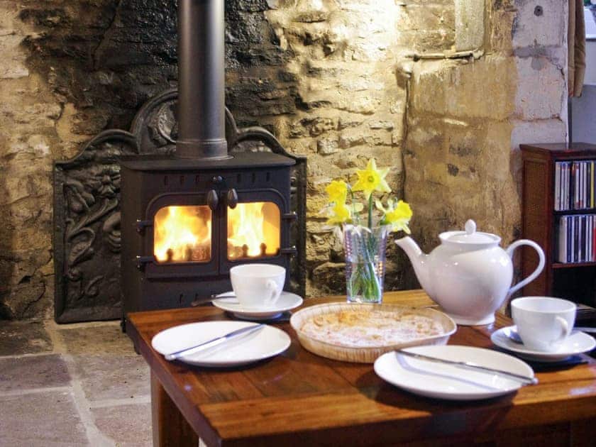 Warm and inviting room with stone fireplace, heritage features and wood burning stove | Ivy Cottage, Chedworth, near Cheltenham