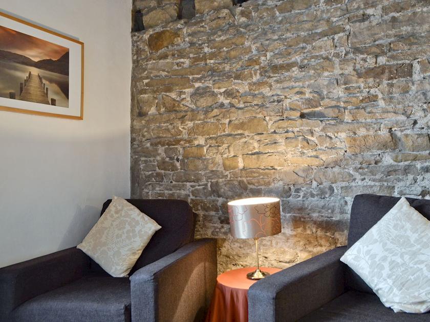 Comfy seating with exposed stone feature wall | Cattlemarket Cottage, Hawes