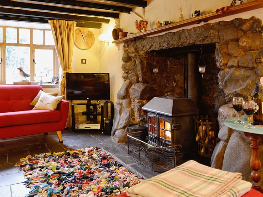The living area features a stone fireplace which houses a wood burning stove | Tremfor, Llwyngwril, near Fairbourne