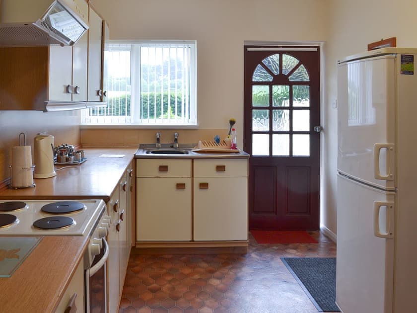 Well-fitted kitchen leading to the garden | Honeysuckle Bungalow - Devon Palms, Maidencombe, near Torquay